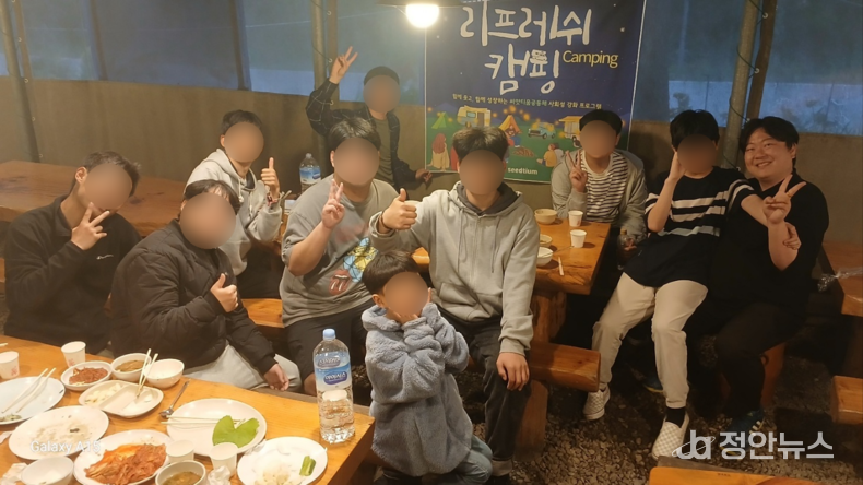 캠프 저녁식사 후 함께한 참가자들. 다양한 연령의 입주자와 초대한 친구들이 웃으며 포즈를 취하고 있다.